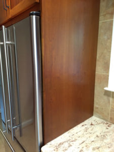 Custom cabinetry surrounding a stainless steel refrigerator.